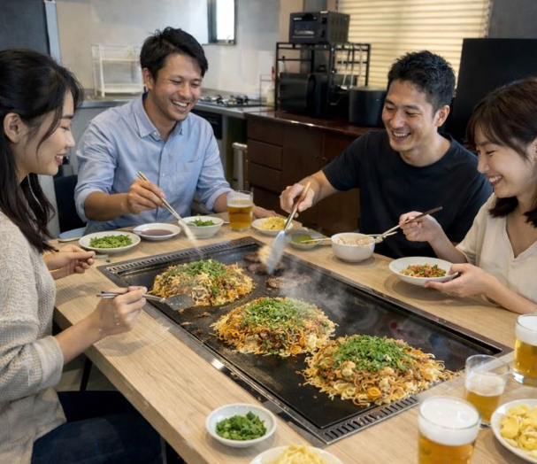 鉄板を囲んでお好み焼き作り体験を楽しむグループ